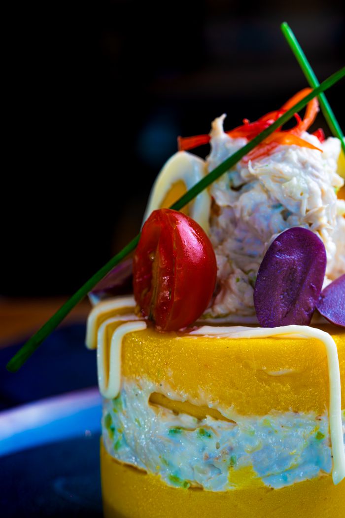 Elegant layered gourmet dish with cherry tomato and colorful edible decor.